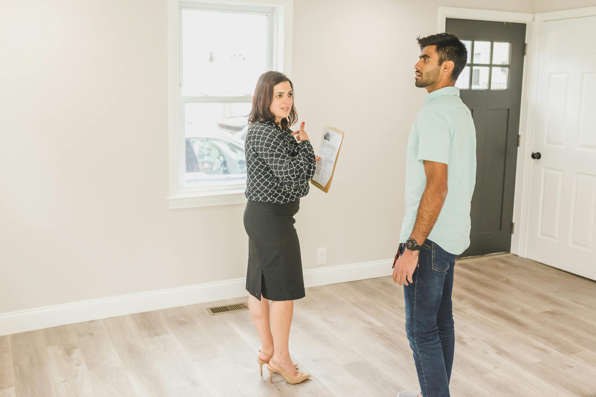Woman showing man around empty house interior.