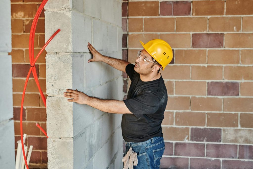 Worker inspecting concrete wall with caution.